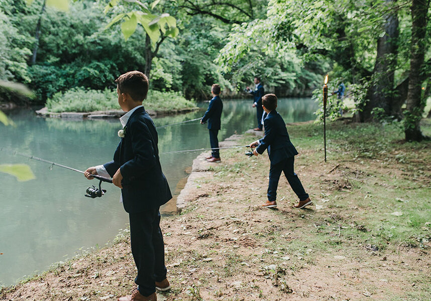 Young boys fishing at Dogwood Canyon after wedding ceremony in their suits.