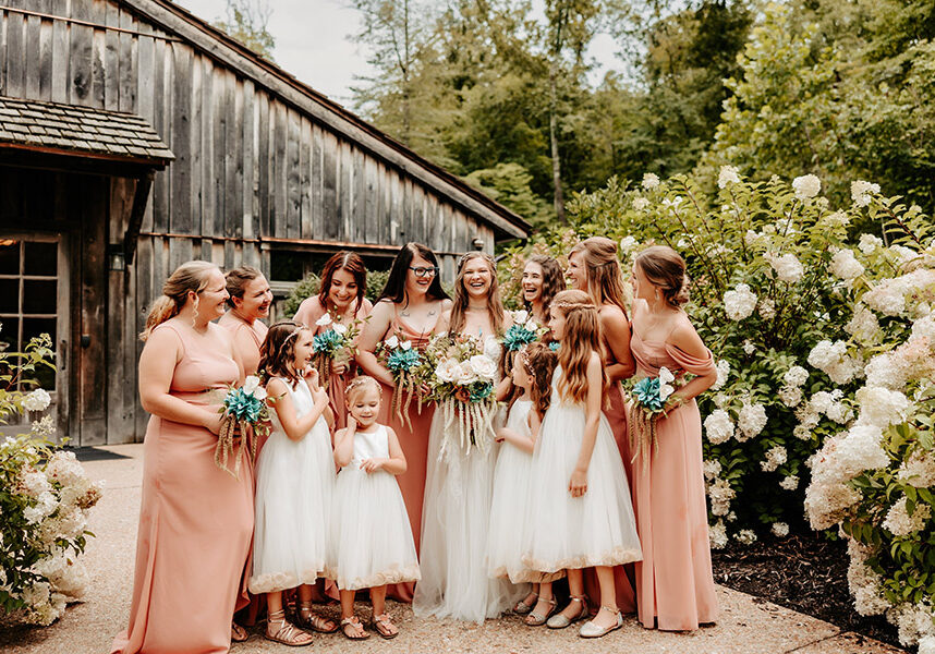 Bride's Maids in soft colors standing in front of the Dogwood Canyon Mill with the flower girls.